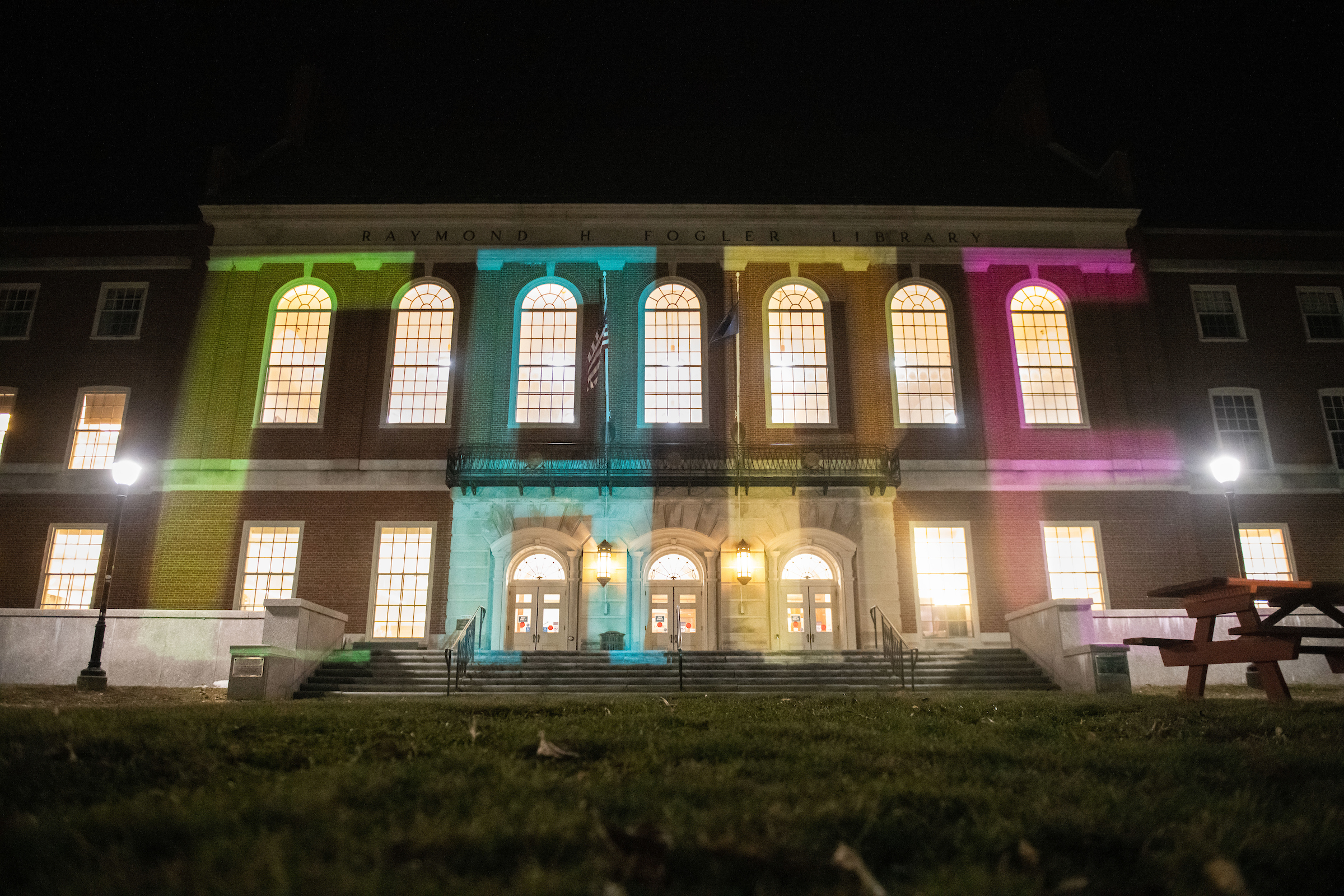 Fogler at night, with CARE projected onto building with multi-colored lights.